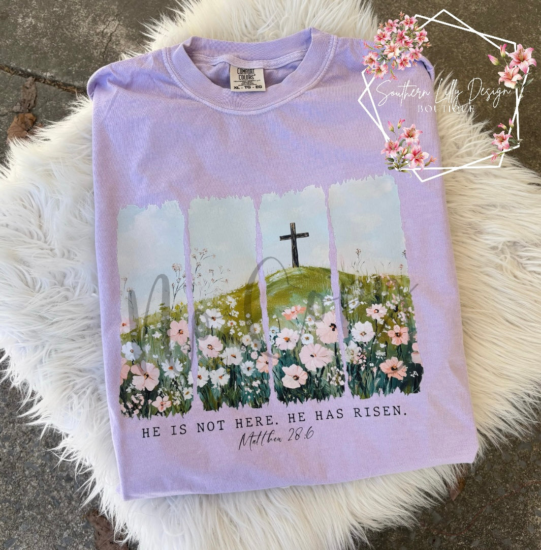 Christian He Is Risen t-shirt – Comfort Colors Easter faith-based graphic tee with Matthew 28:6 Bible verse and floral cross design.
