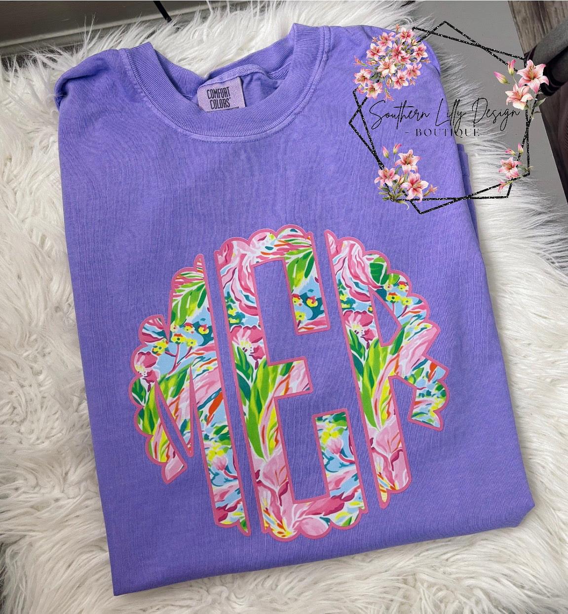 Purple t-shirt with colorful floral letters on a white fluffy surface