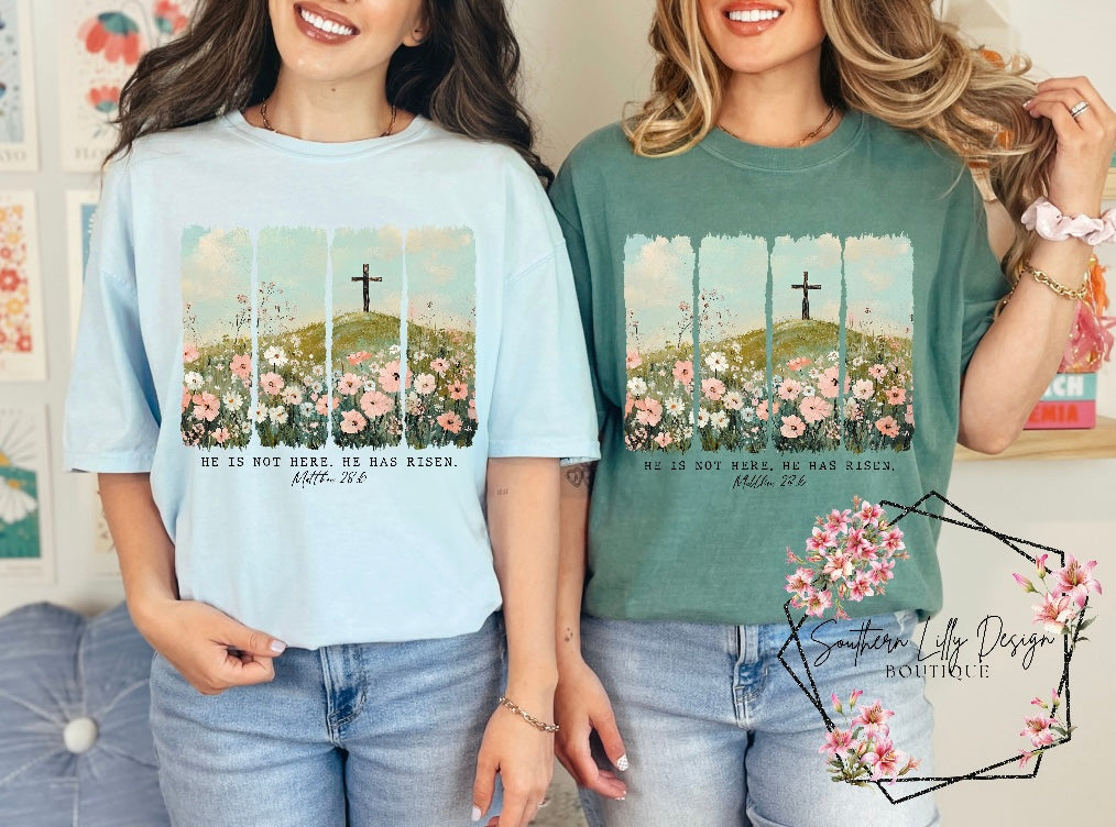 Christian He Is Risen t-shirt – Comfort Colors Easter faith-based graphic tee with Matthew 28:6 Bible verse and floral cross design.